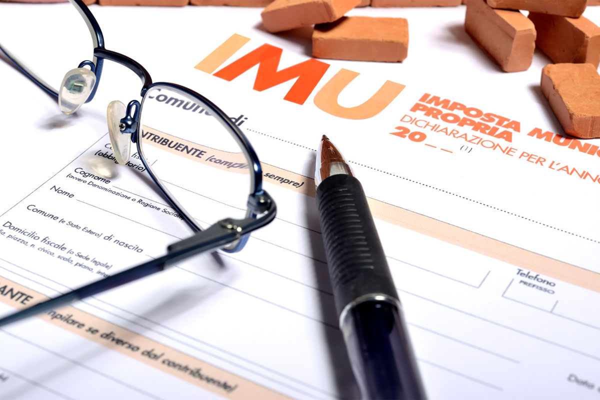 documentazione IMU con sopra una penna e un paio di occhiali