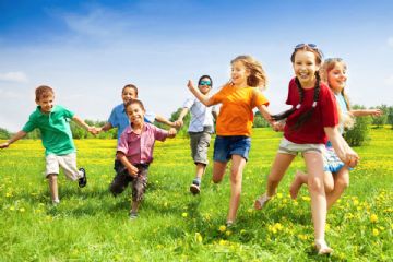 bambini che corrono felici sul prato in una giornata di sole