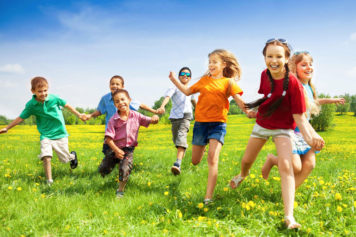 bambini che corrono felici sul prato in una giornata di sole