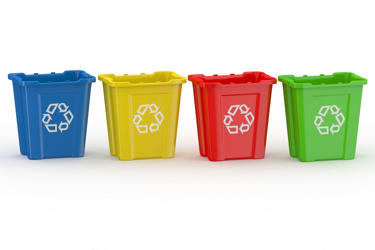 quattro bidoni della spazzatura con i colori della raccolta differenziata (blu, giallo, rosso e verde)